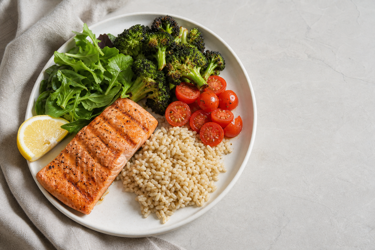 Balanced meal with salmon, brown rice, broccoli, tomatoes, and leafy greens